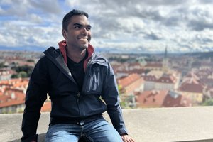 A man sitting on a ledge overlooking a city.